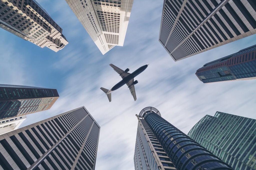 Ein Flugzeug fliegt über den Hochhäusern von Singapur.