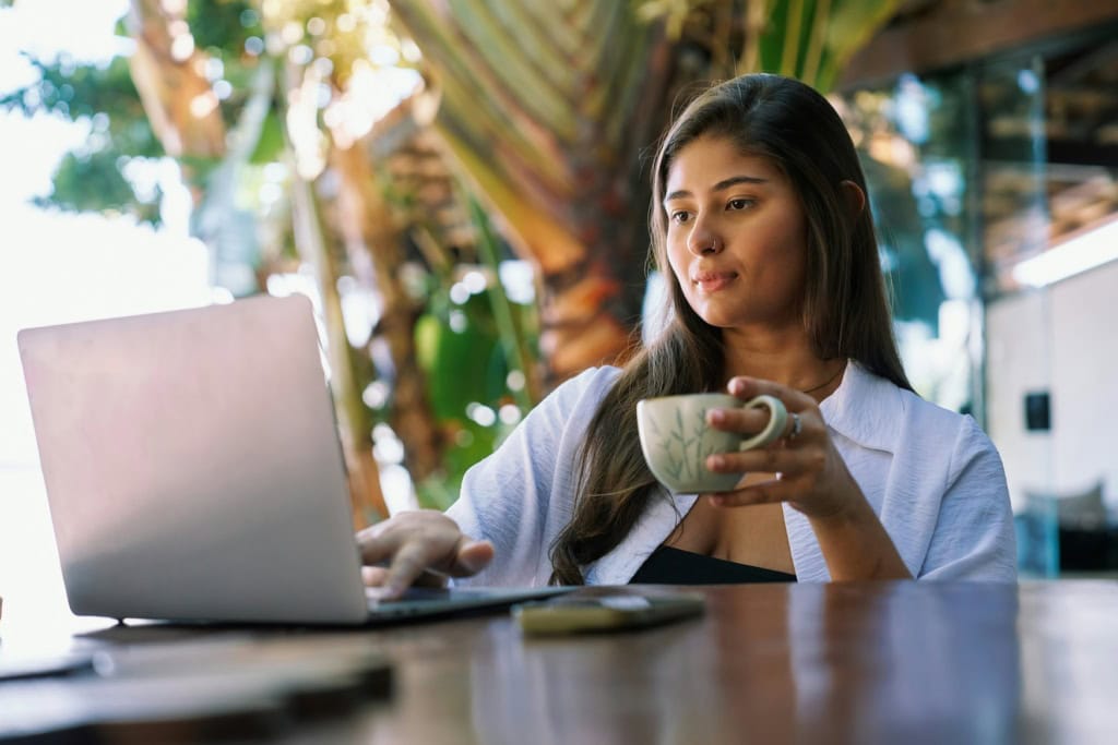 Eine Frau arbeitet im Freien an ihrem Laptop.
