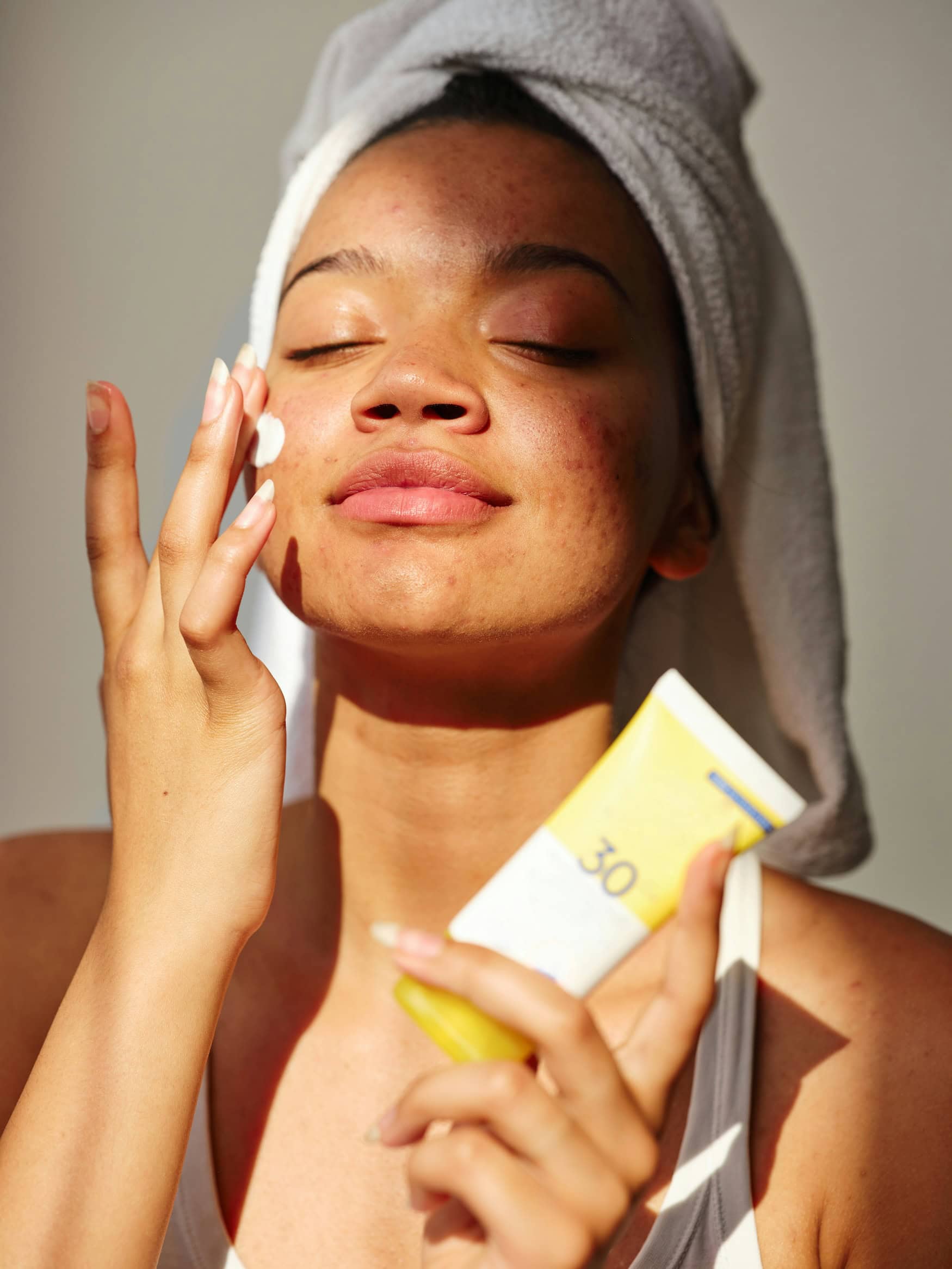 Eine Frau trägt im Gesicht Sonnencreme auf – nach einem Retinol-Peeling ist das wichtig. 