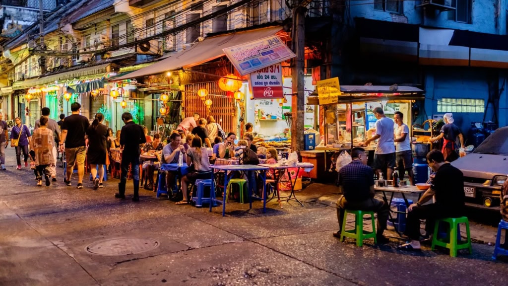 Menschen sitzen vor einem Restaurant in Bangkok.