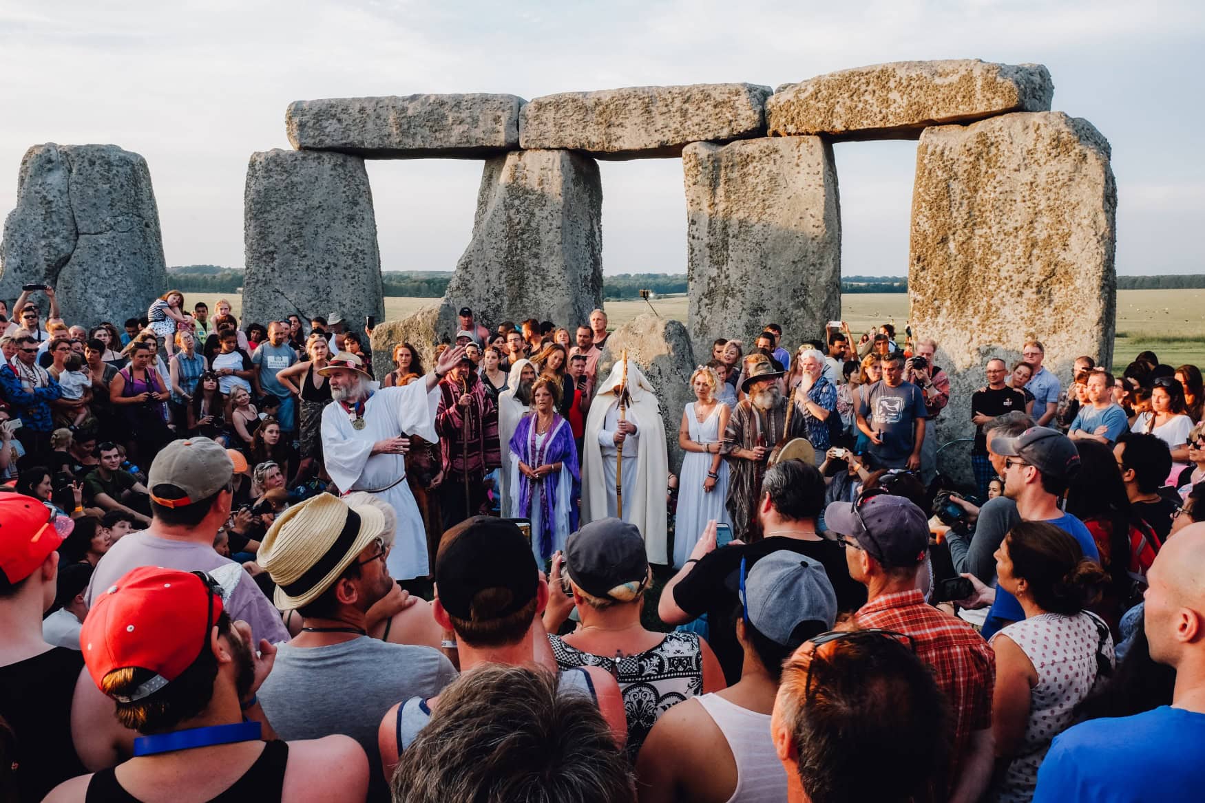 Im inneren Kreis des Megalithen-Denkmals Stonehenge in England steht eine große Menschenmenge, geringt um einige Menschen, die als keltische Druiden gewandet sind.