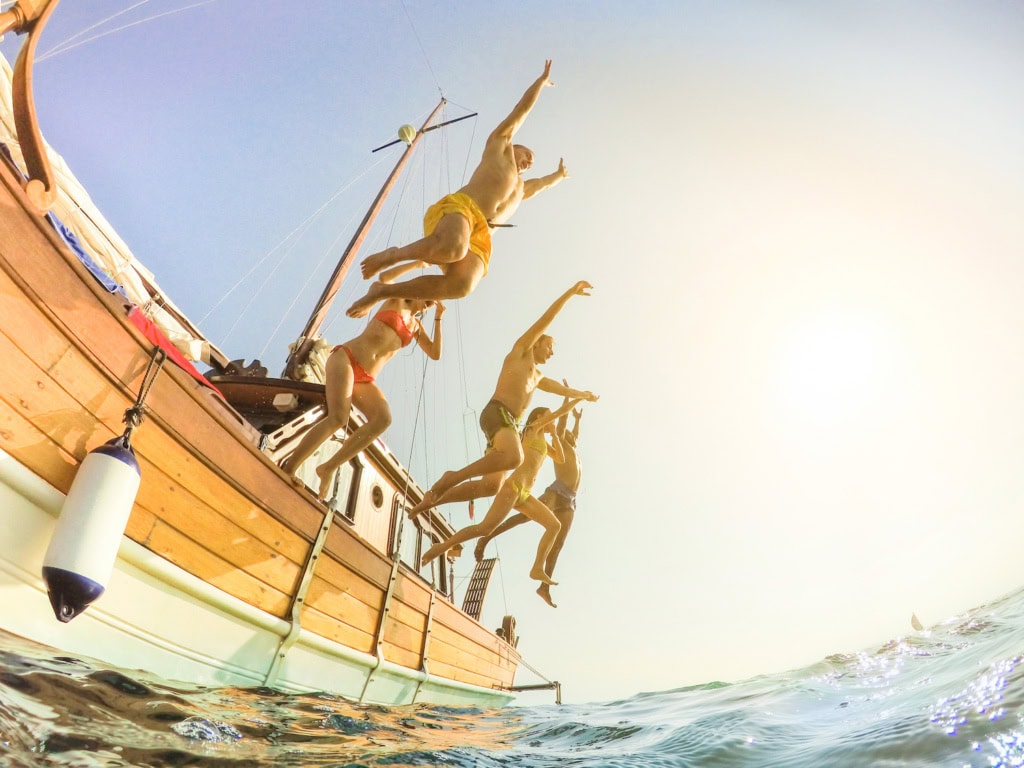 Familie springt von Segelboot ins Wasser