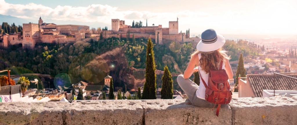Junge Frau mit Sonnenhut blickt auf die Alhambra in Granada
