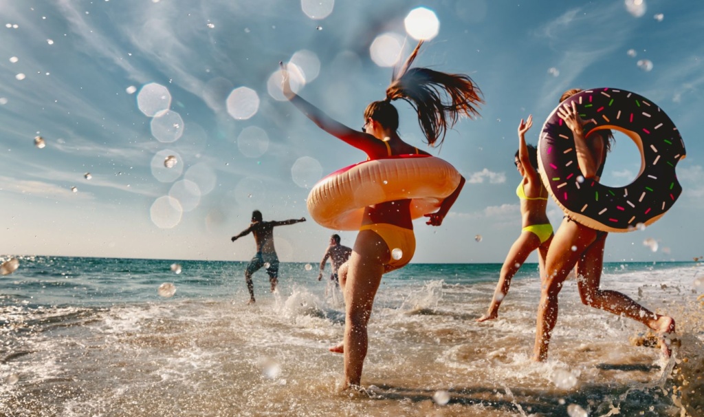 Zwei Männer und drei Frauen springen freudig ins Meer