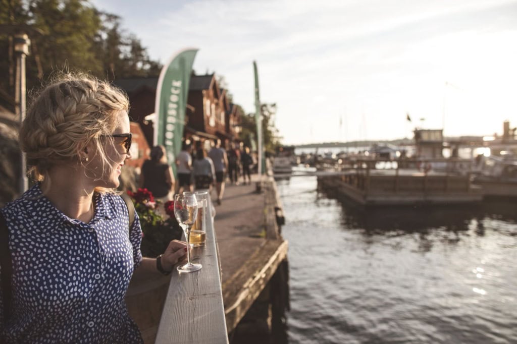 Frau gönnt sich Drink am Hafen auf Insel Fjäderholmarna