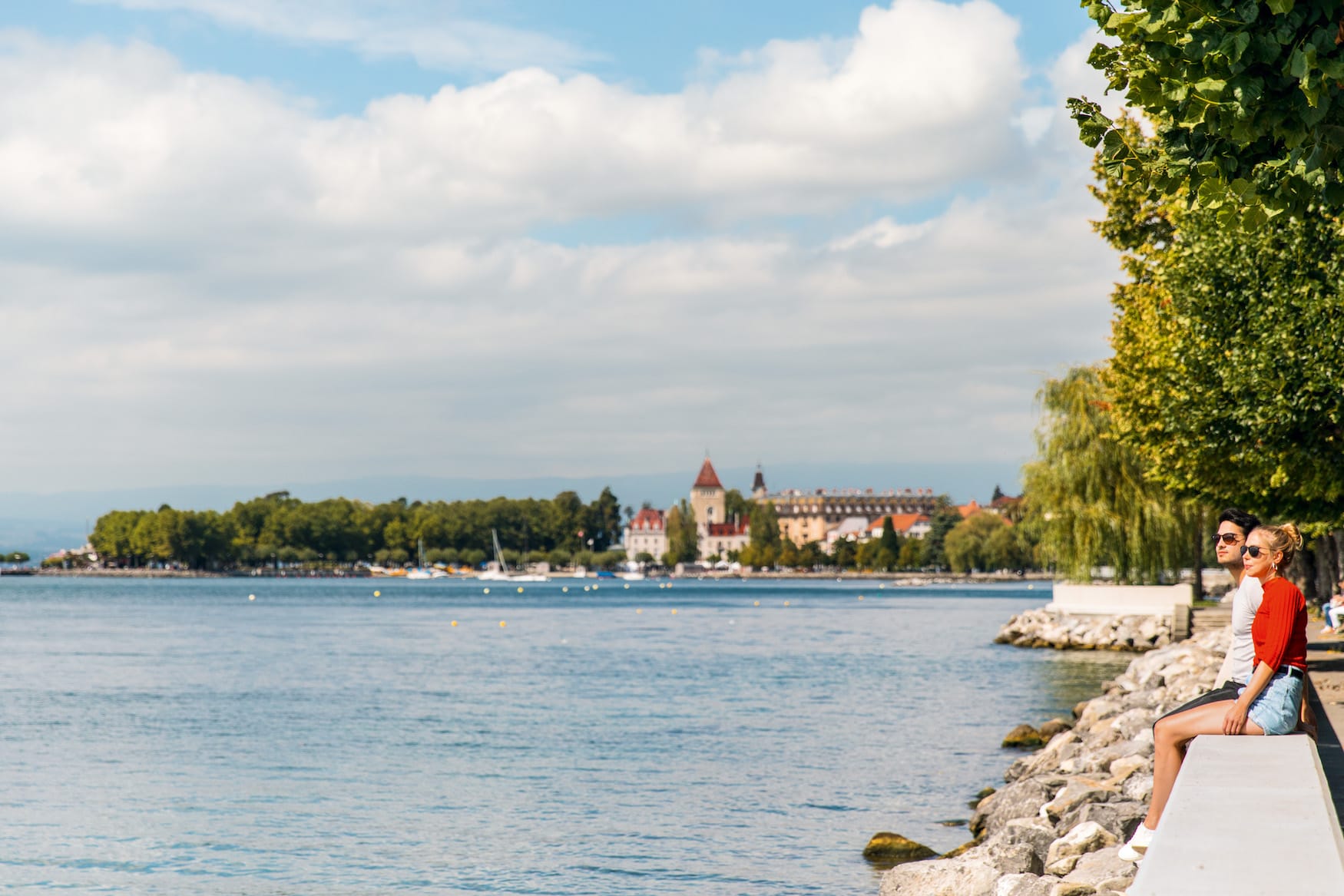 Junges Paar sitzt am Quai d'Ouchy Ufer, Lausanne, Schweiz.