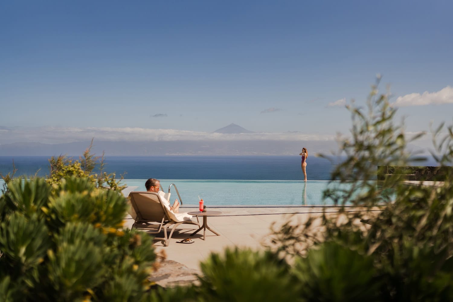 Mann auf Liege am Infinity-Pool und Frau stehend am Pool im Bancal Hotel & Spa