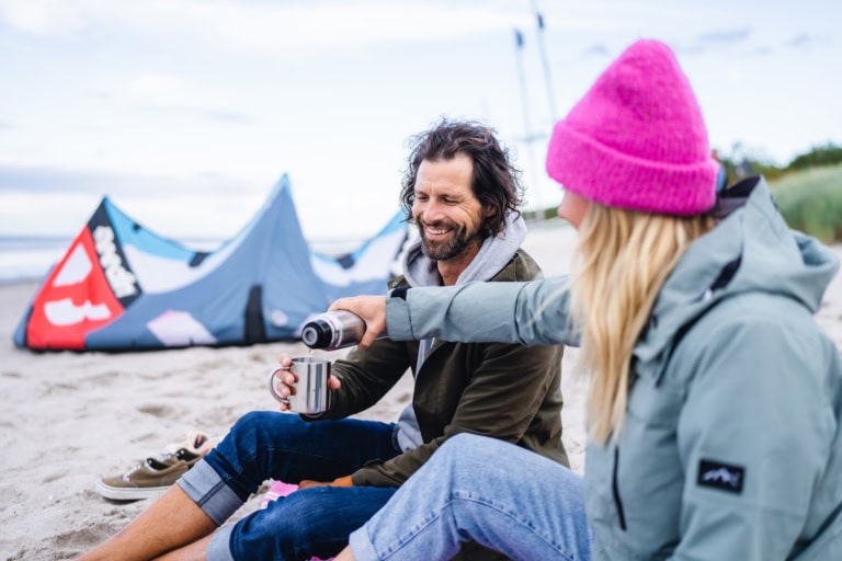 Ein Paar genießt heißen Tee am Strand im Herbst an der Ostsee.