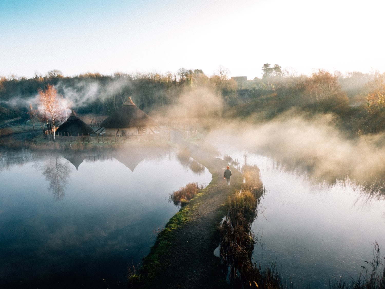 Mann läuft über einen Steg im Nebel im The Irish Heritage Park in Irland