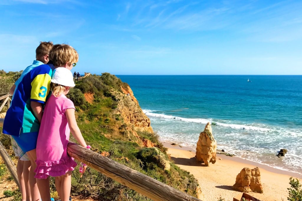 Kinder wandern bei den Klippen über dem Strand Praia dos Tres Castelos an der Algarve