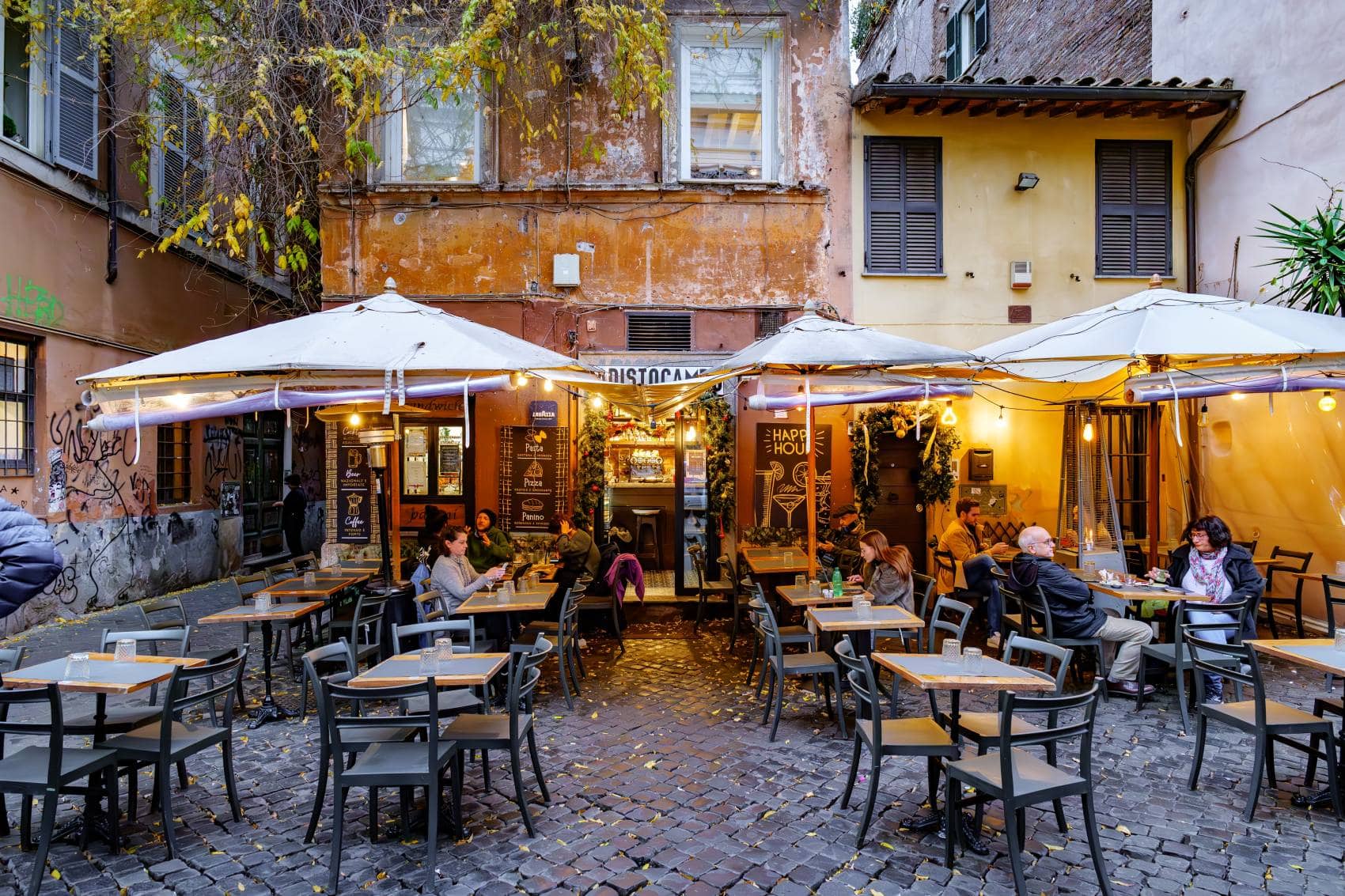 Gäste sitzen vor einer Taverne im Stadtteil Trastevere in Rom