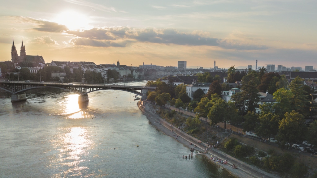 Drohnenaufnahme vom Rheinschwimmen und der Stadt Basel im Abendlicht