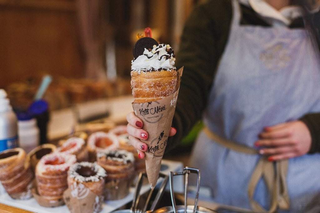 Frau hält Baumstriezeln mit Sahne und Oreos