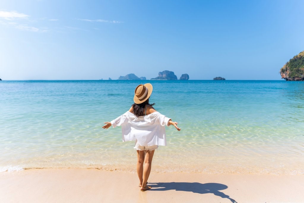 Frau steht am Meer im Urlaub