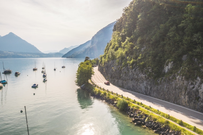 Roadtrip durch die Schweiz: Ein Mazda fährt entlang der Seestrasse am Thunersee, links der Niesen