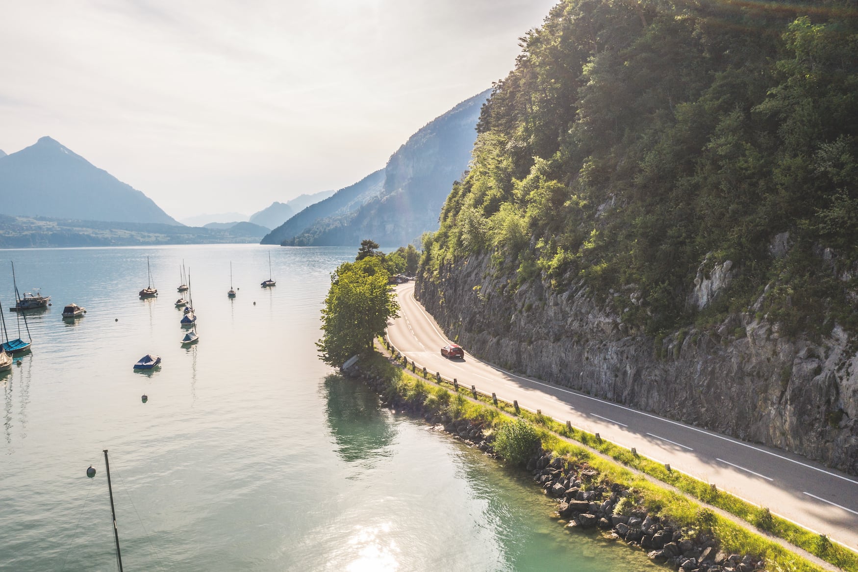 Roadtrip durch die Schweiz: Ein Mazda fährt entlang der Seestrasse am Thunersee, links der Niesen