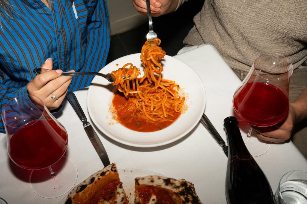 Zwei Personen teilen sich einen Teller Pasta.