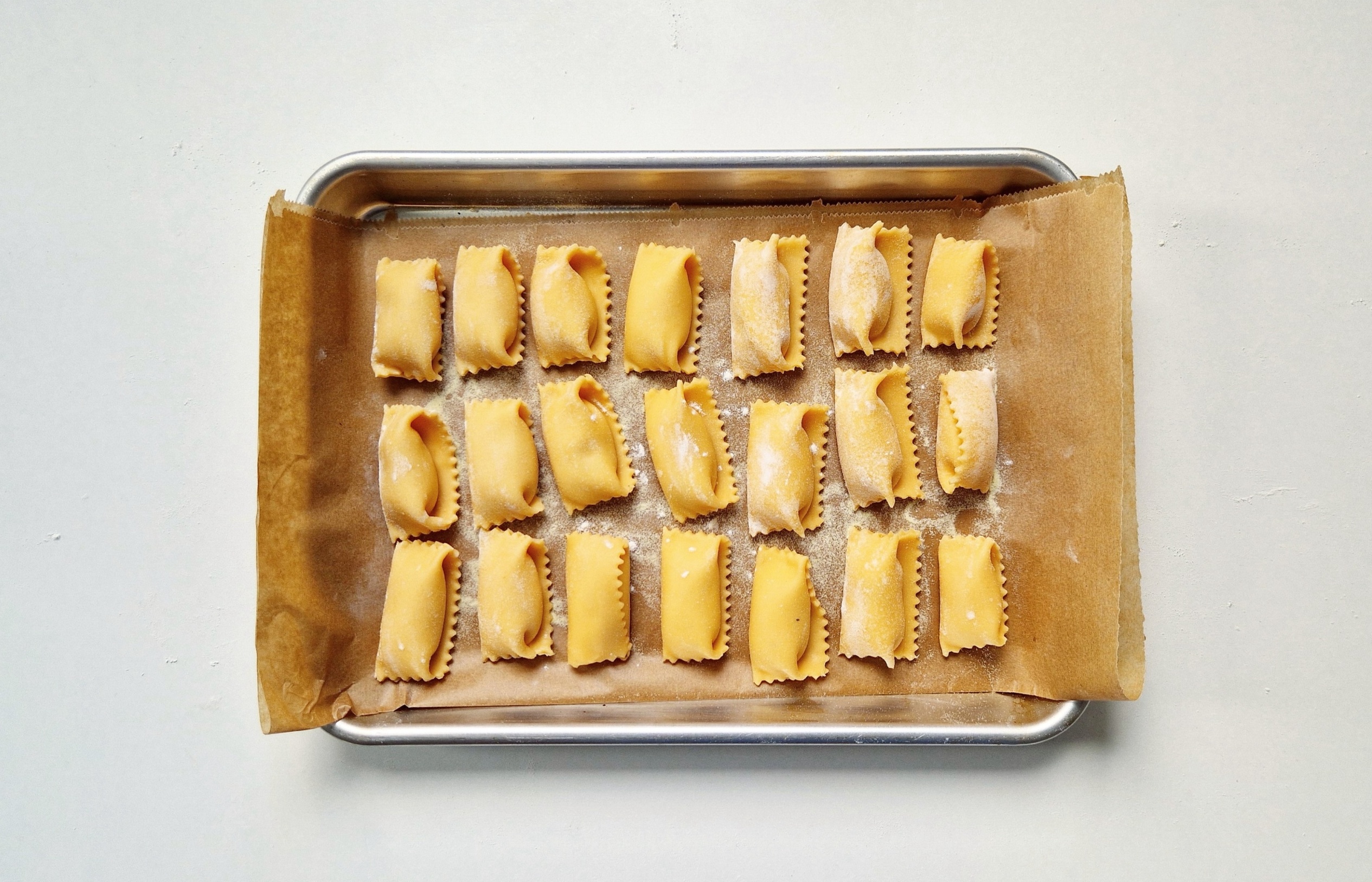 Ungekochte Agnolotti del plin auf einem Tablett.