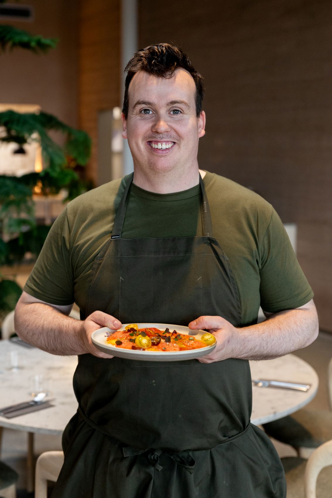 Chefkoch Gisli Matt hält lächelnd ein Gericht in der Hand