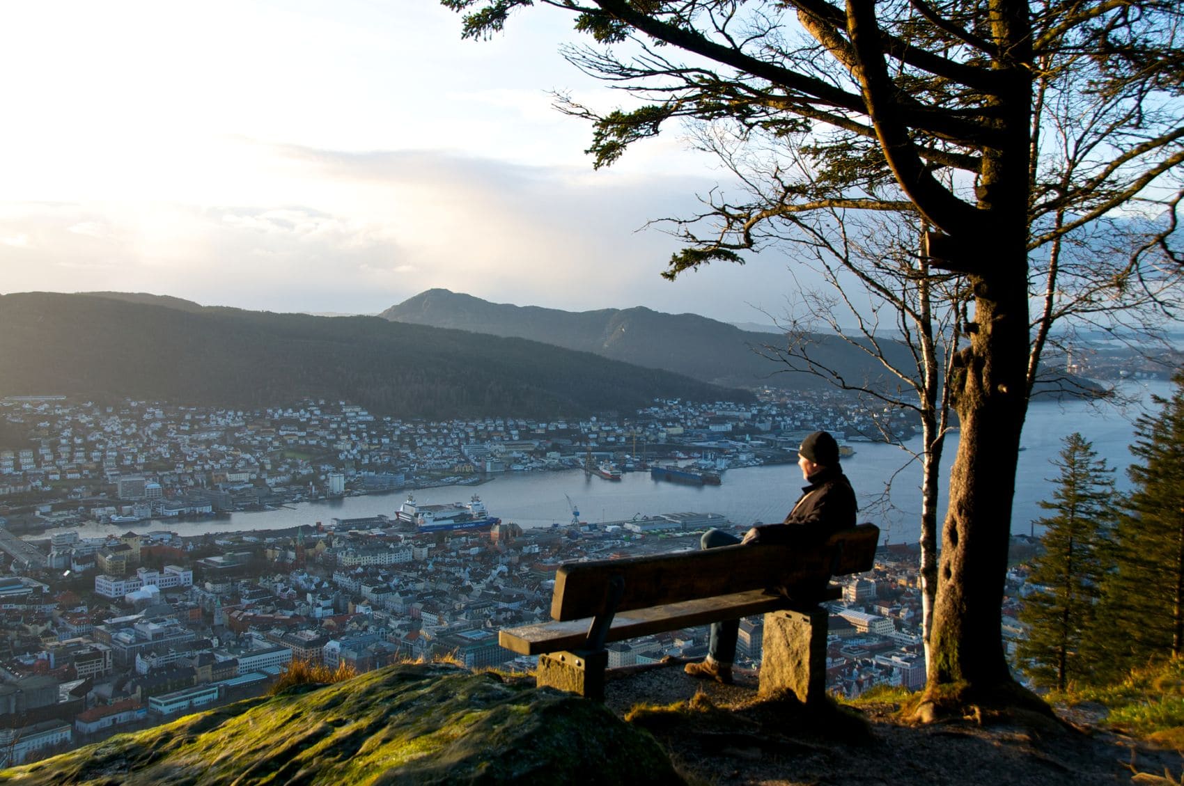 Mann sitzt am Aussichtspunkt Floien in Bergen auf einer Bank und genießt den Blick auf die Stadt 