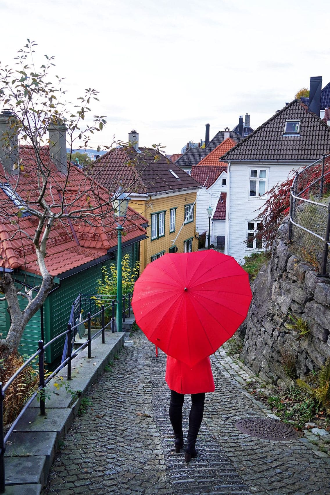 Touristin mit rotem Regenschirm flaniert durch Bergen, Norwegen 