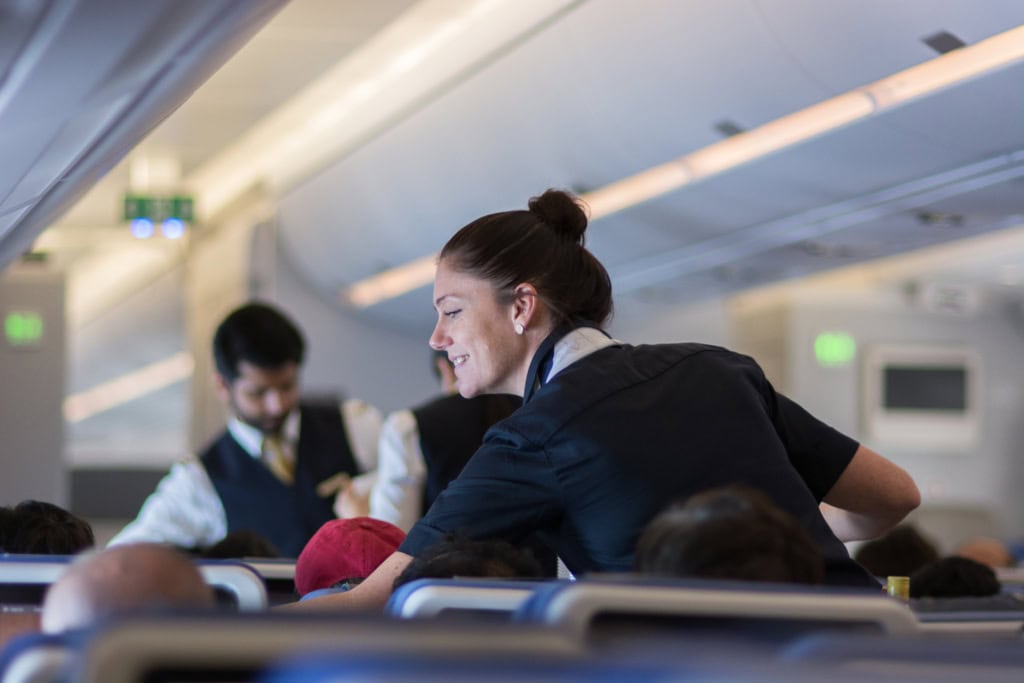 Eine Flugbegleiterin der Lufthansa serviert Essen.