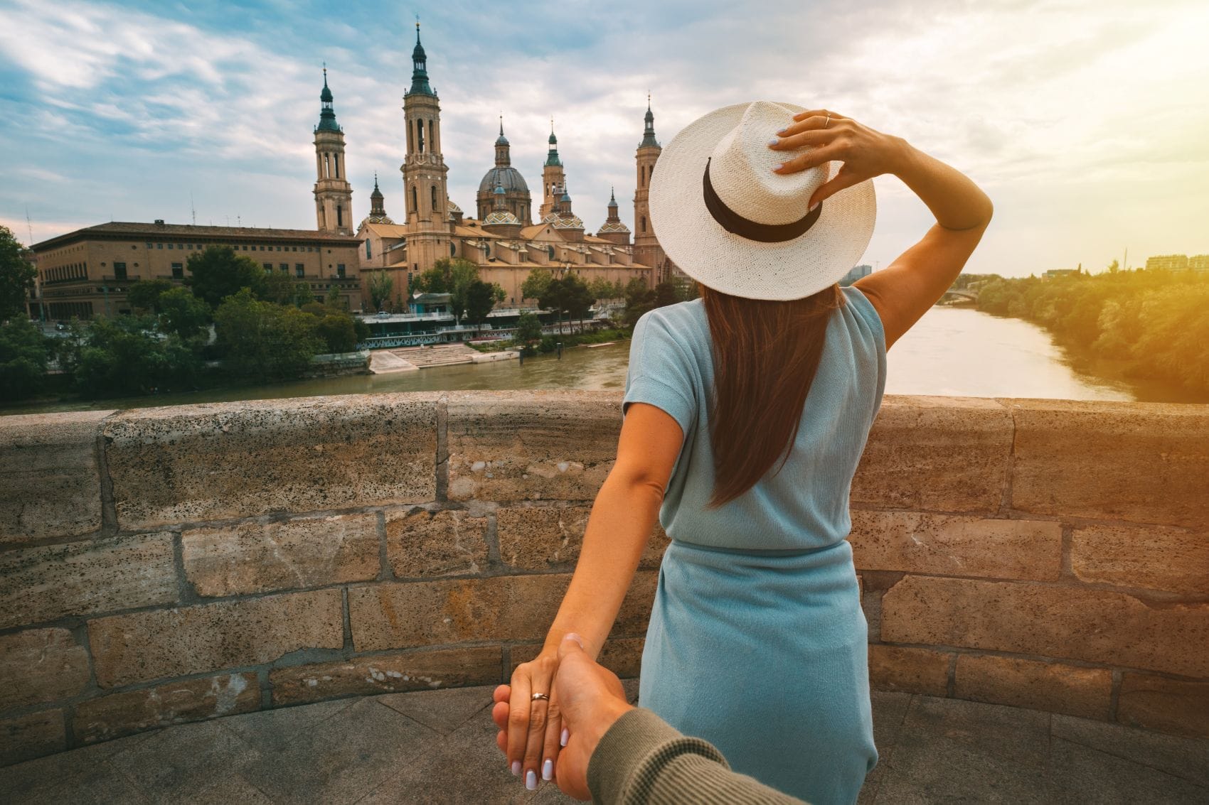 Frau mit Sonnenhut hält Hand eines Mannes und blickt auf die Kathedrale in Saragossa 