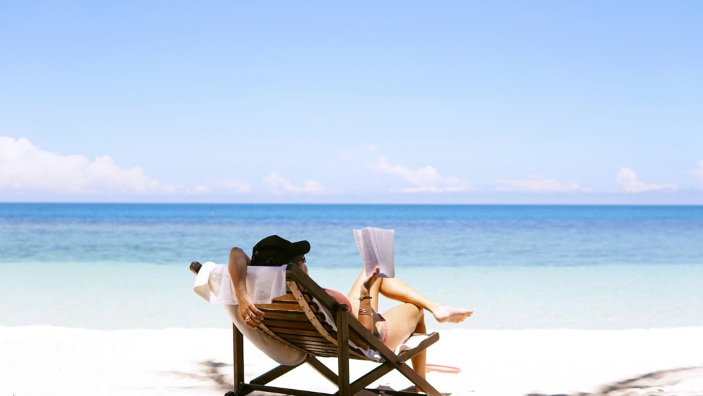 Frau im Liegestuhl am Meer beim Lesen