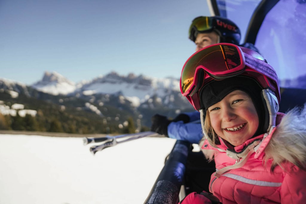Lachendes Kind im Winterurlaub im Skigebiet Plose, Berg im Hintergrund