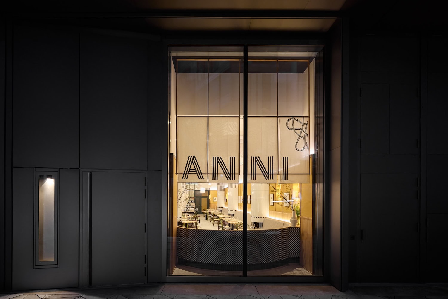 Eingang der Brasserie Annie im Dunkeln, durch eine grosse Glastür gesehen