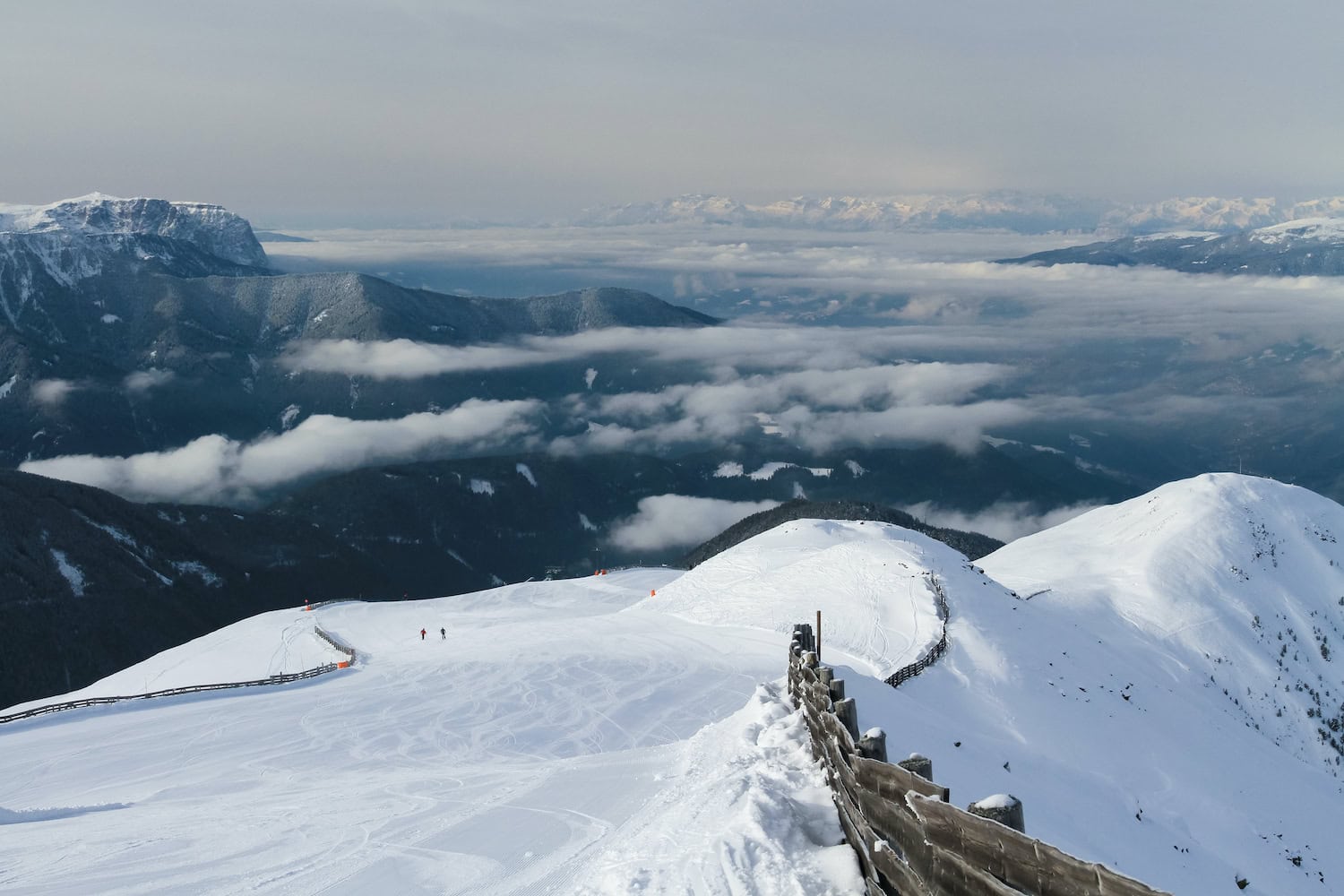 Trametschpiste von oben ohne Skifahrer mit Blick ins wolkenverhangene verschneite Tal