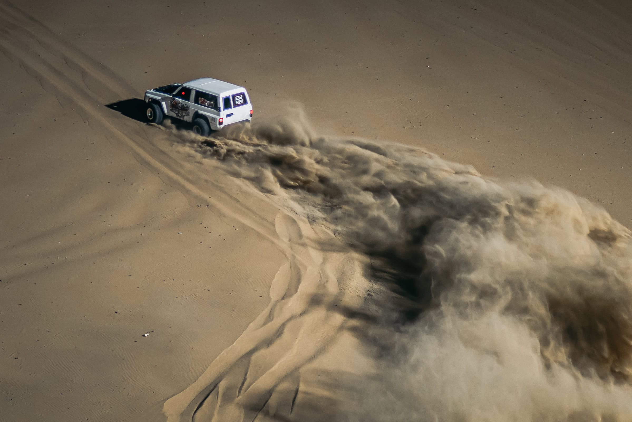 Ein Auto fährt durch die Wüste in Abu Dhabi.