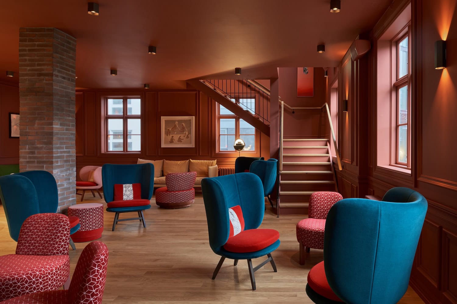 Gemütliches Lounge mit roten Wänden, blauen Sesseln und Teppichstühlen, schönes Ambiente, stylischer Stil, Reisenexclusiv.