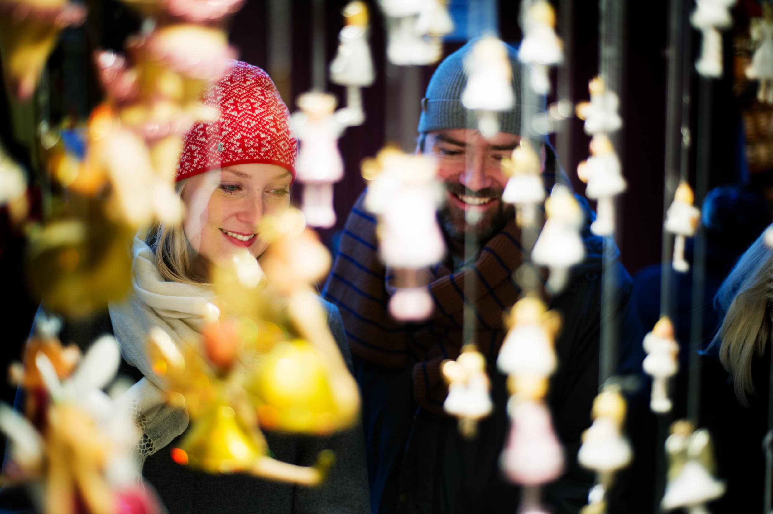 Eine Frau und ein Mann stehen an einem Stand auf einem Weihnachtsmarkt.