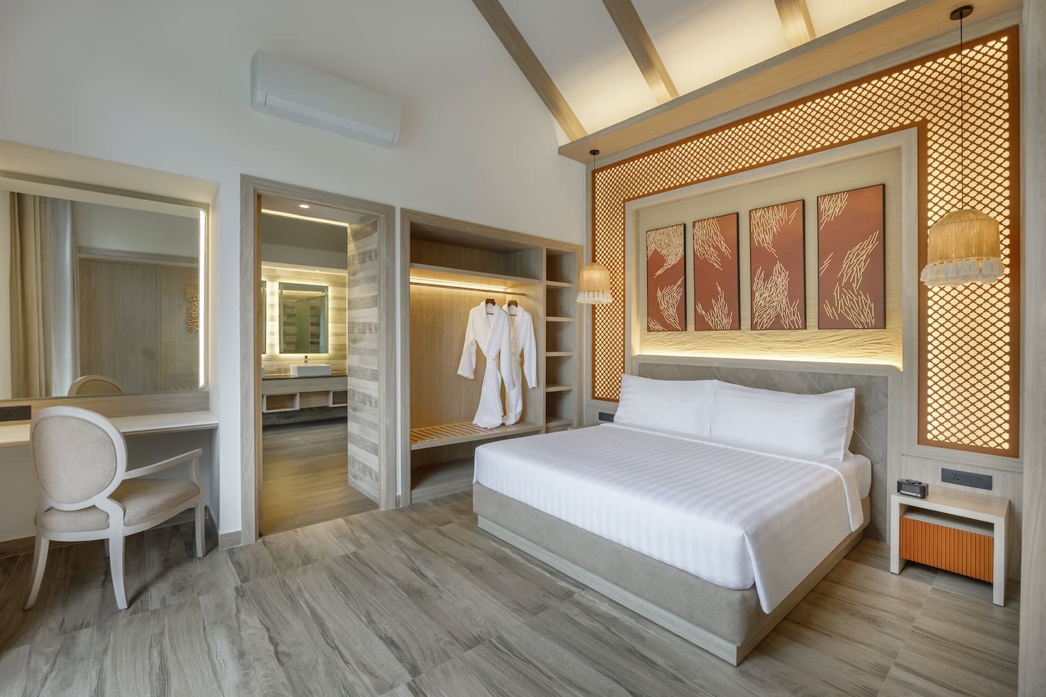 Himalalyan Hideaway Resort, Zimmer mit großem Bett in hellen Farben und nepalesischer Kunst an der Wand über dem Bett. Die Decke ist sehr hoch und im Schrank hängt ein weißer Bademantel. Eine Tür zum Bad geht an der Seite ab.