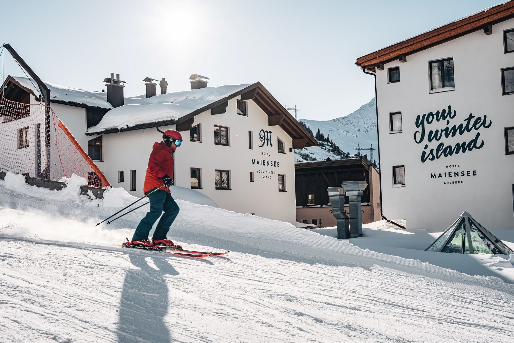 Skifahrer fährt auf Piste direkt vor dem Hotel Maiensee entlang