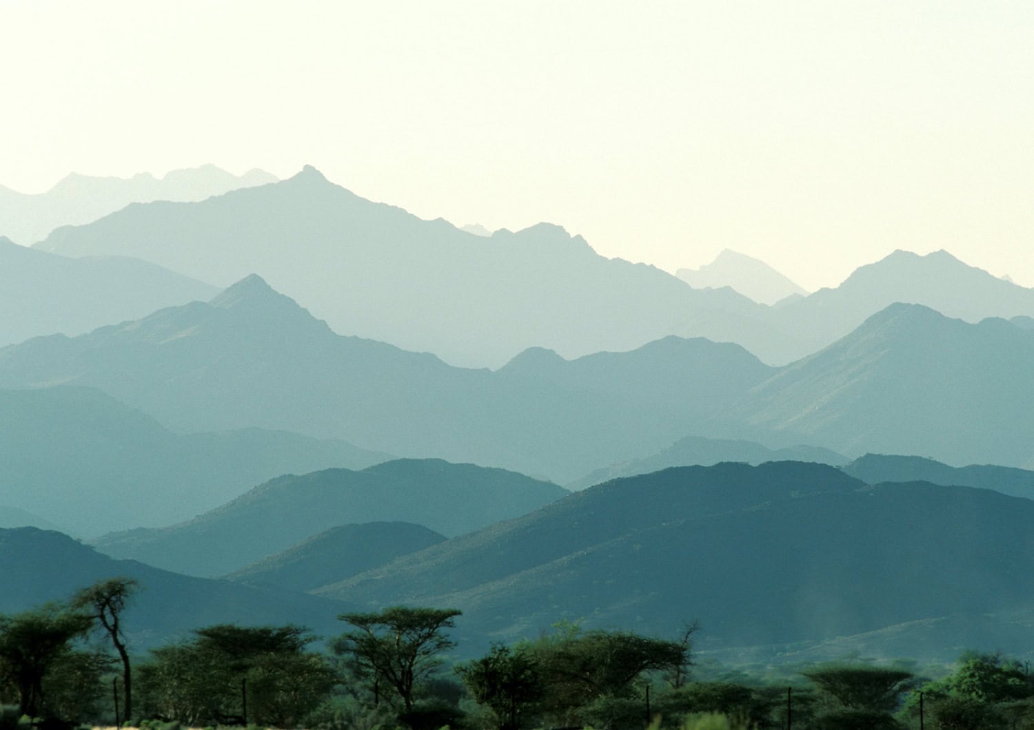 Blick über die Berge, die im Hintergrund schemenhaft wie Schichten erkennbar sind.