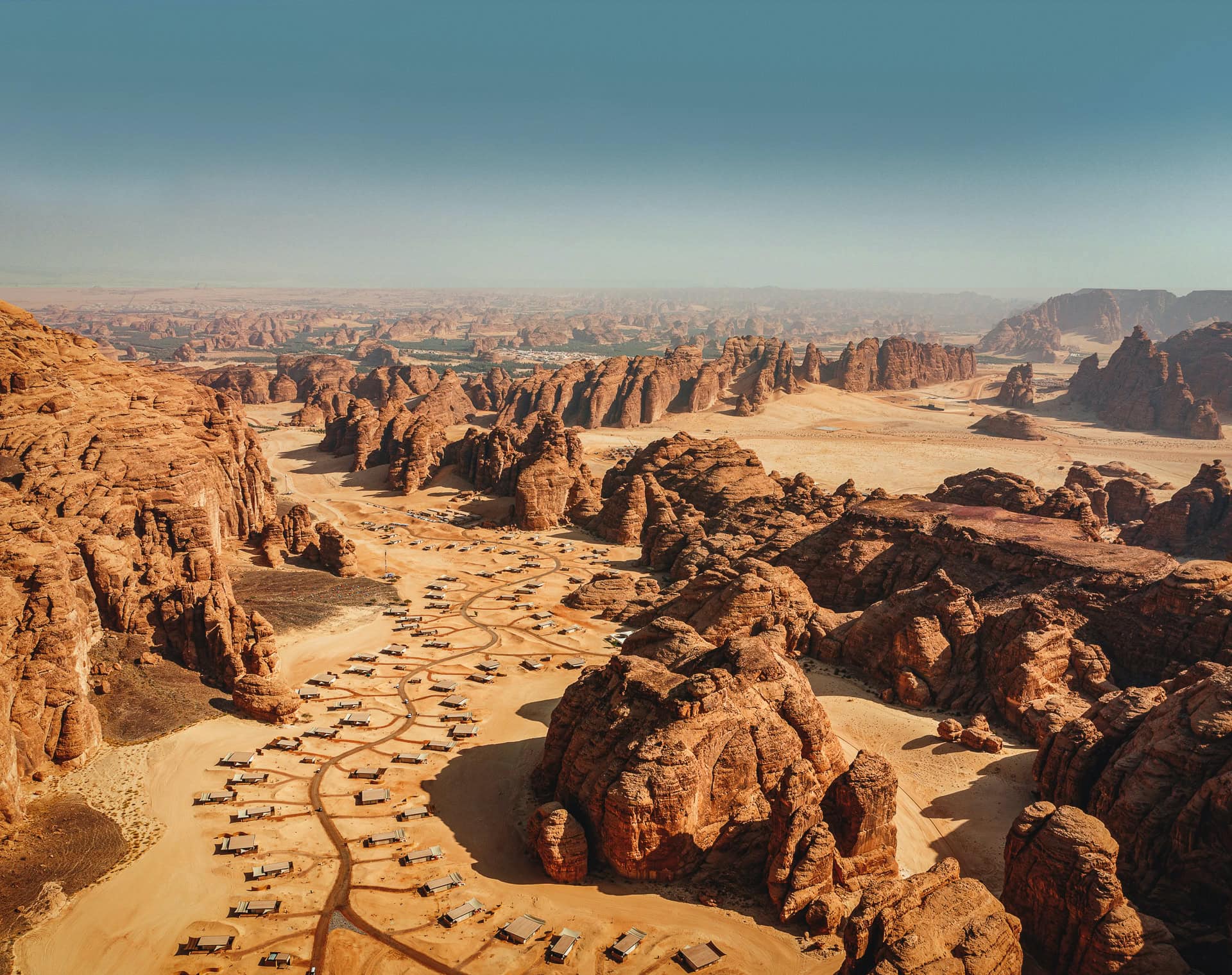 Our Habitas Alula: Dronenfoto auf die Anlage mit vielen astförmig angeordneten Villen inmitten von hohen Felsen in der Wüstenlandschaft