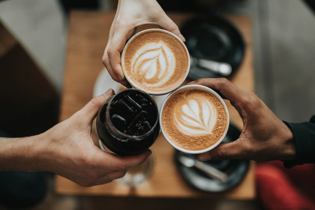 drei Menschen halten Kaffee
