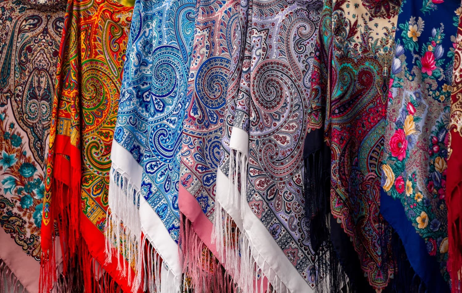 Verschiedene Schals mit Paisleymuster, die nebeneinander hängen.