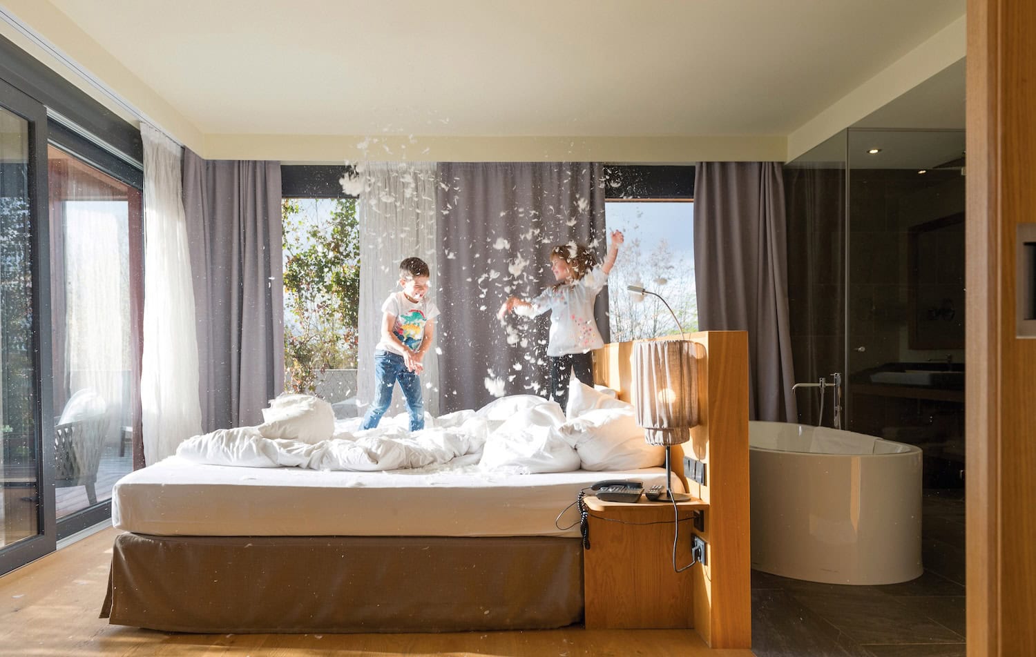 Suite mit sehr fröhlichen Kindern, die auf dem Bett springen bei einer Kissenschlacht, im Ulrichshof.