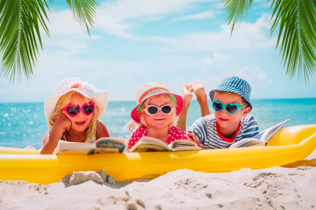 Kinder liegen am Strand und lesen