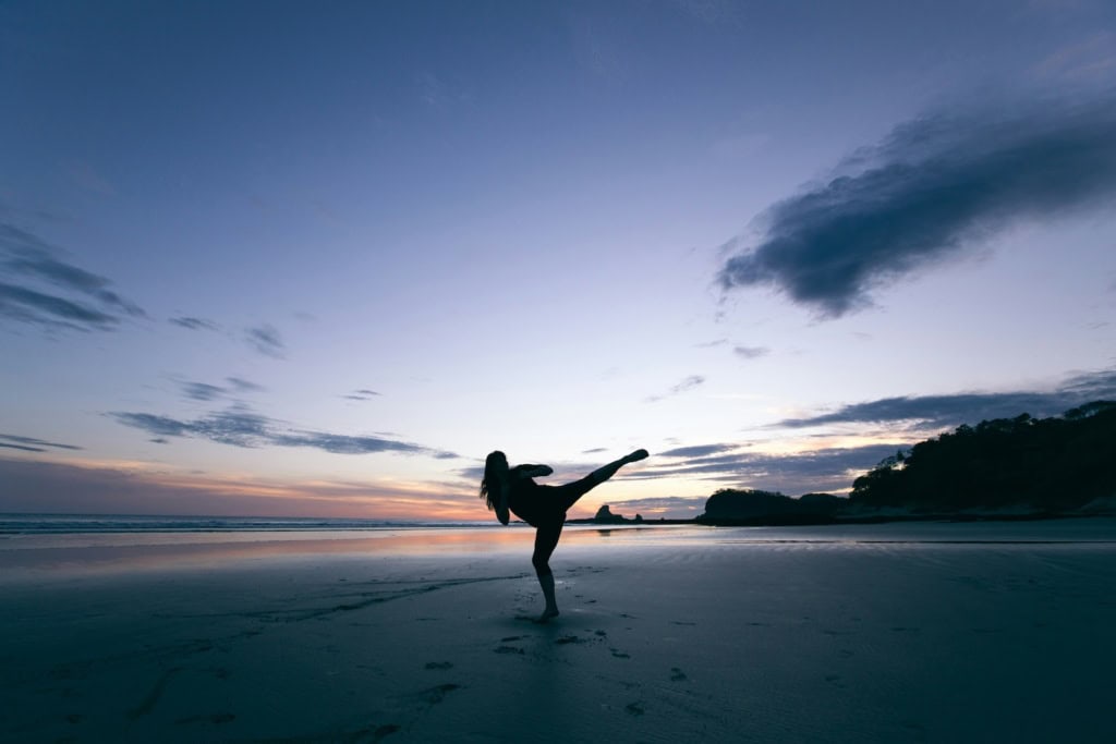 Longevity Reiseziele: Mensch macht Sport am Strand in der Abenddämmerung