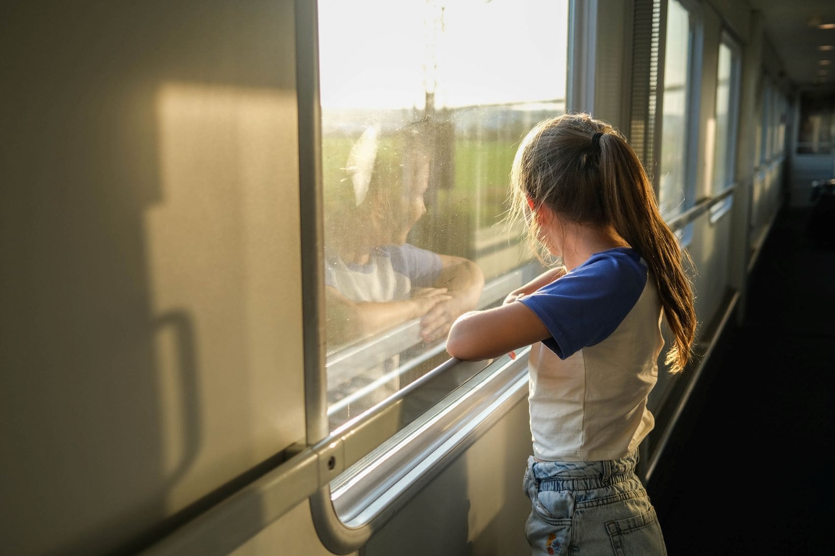 Mädchen steht im Gang eines Nachtzuges und blickt am Morgen aus dem Fenster 