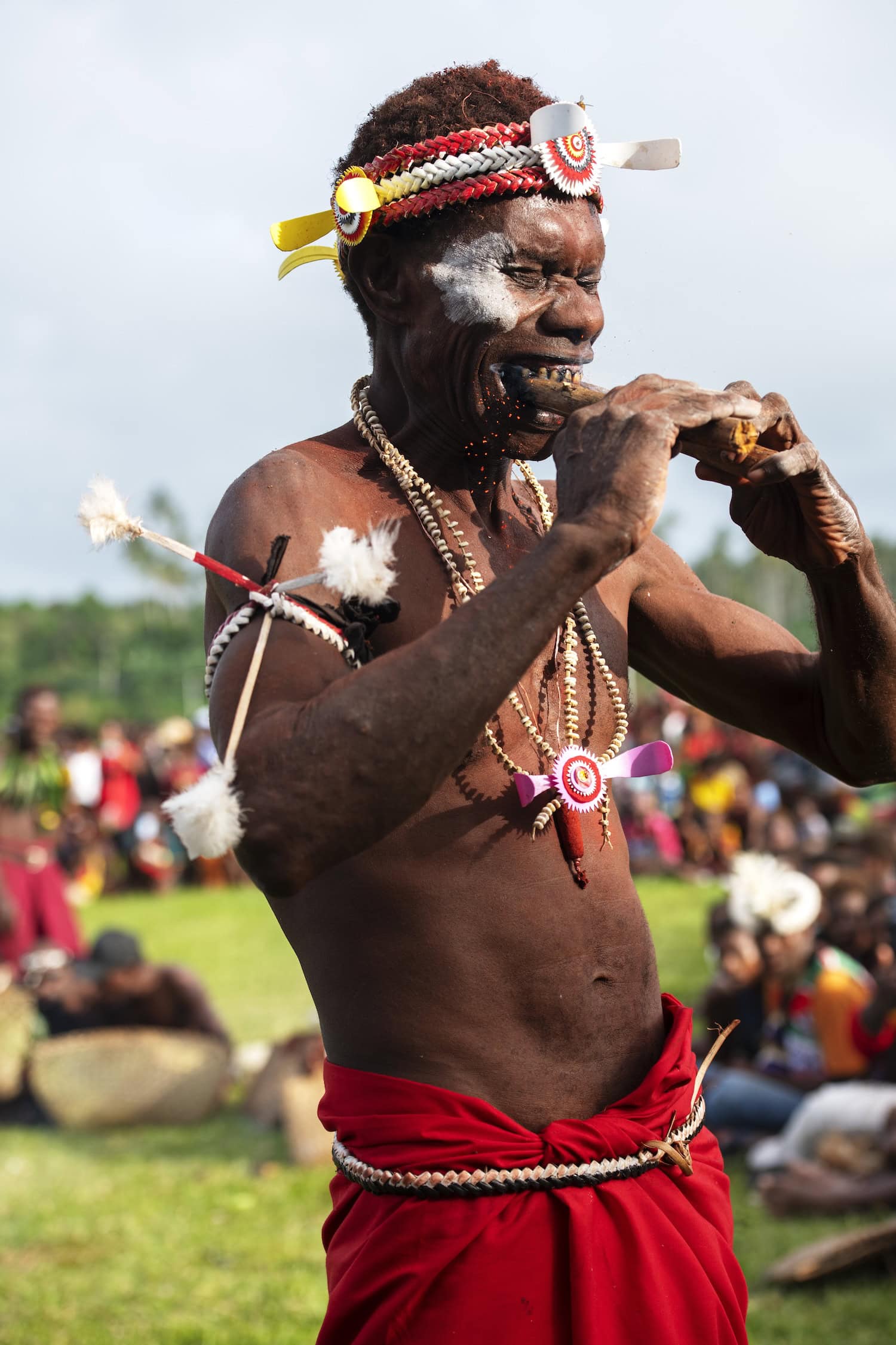 Akteur beim Maskenfest in Kokopo in Papua-Neuguinea, der auf einen heißen Holzscheit beißt