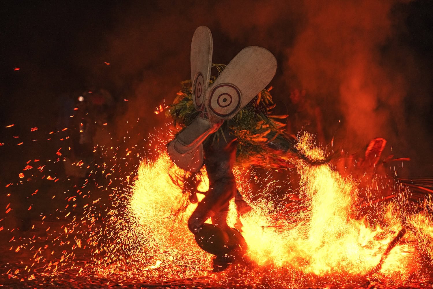 Mensch tanzt in Maske ums Feuer beim Maskenfest in Kokopo in Papua-Neuguinea