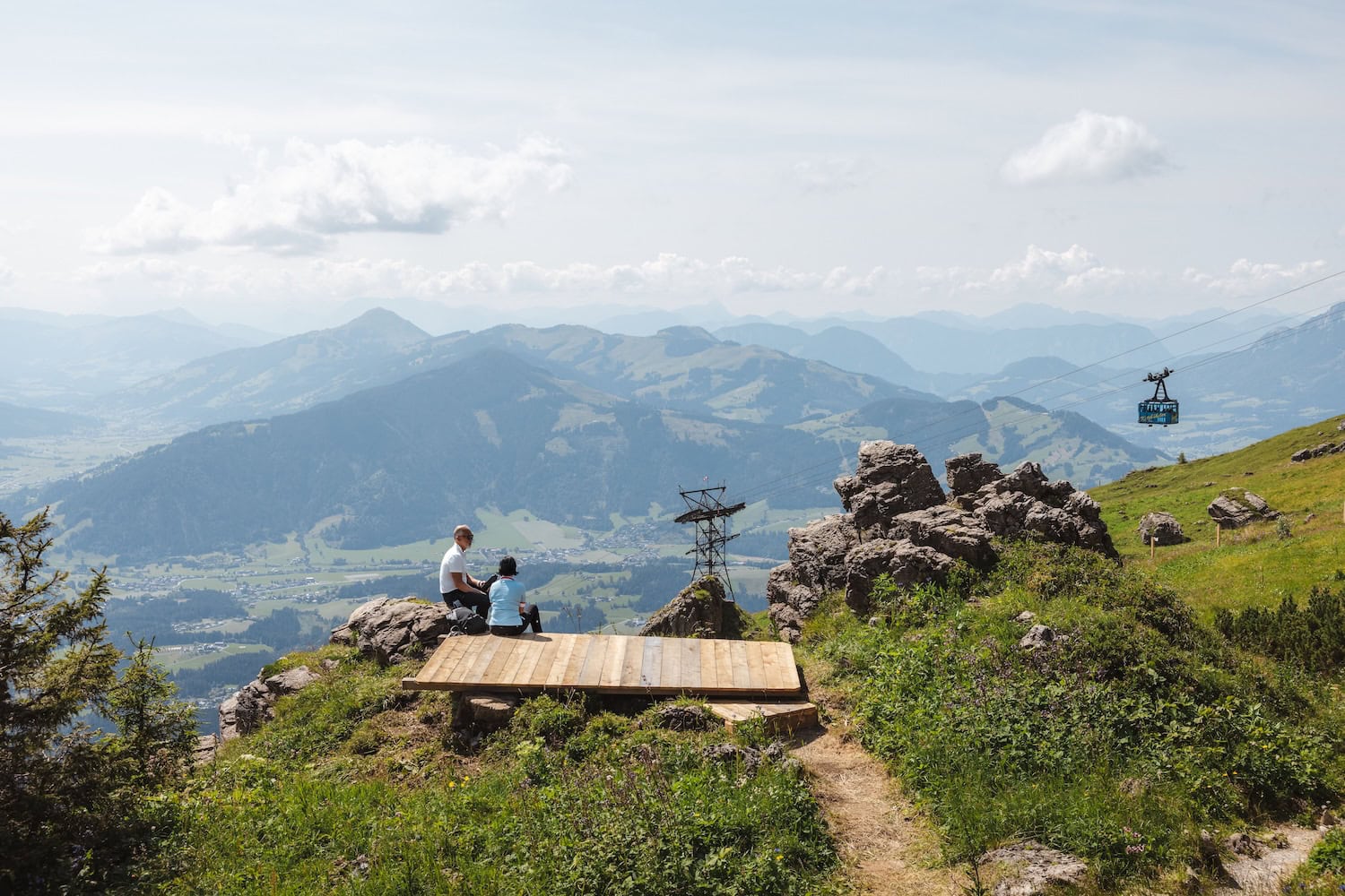 Mann und Frau sitzen vor einer Bergbahn in Kitzbühel.