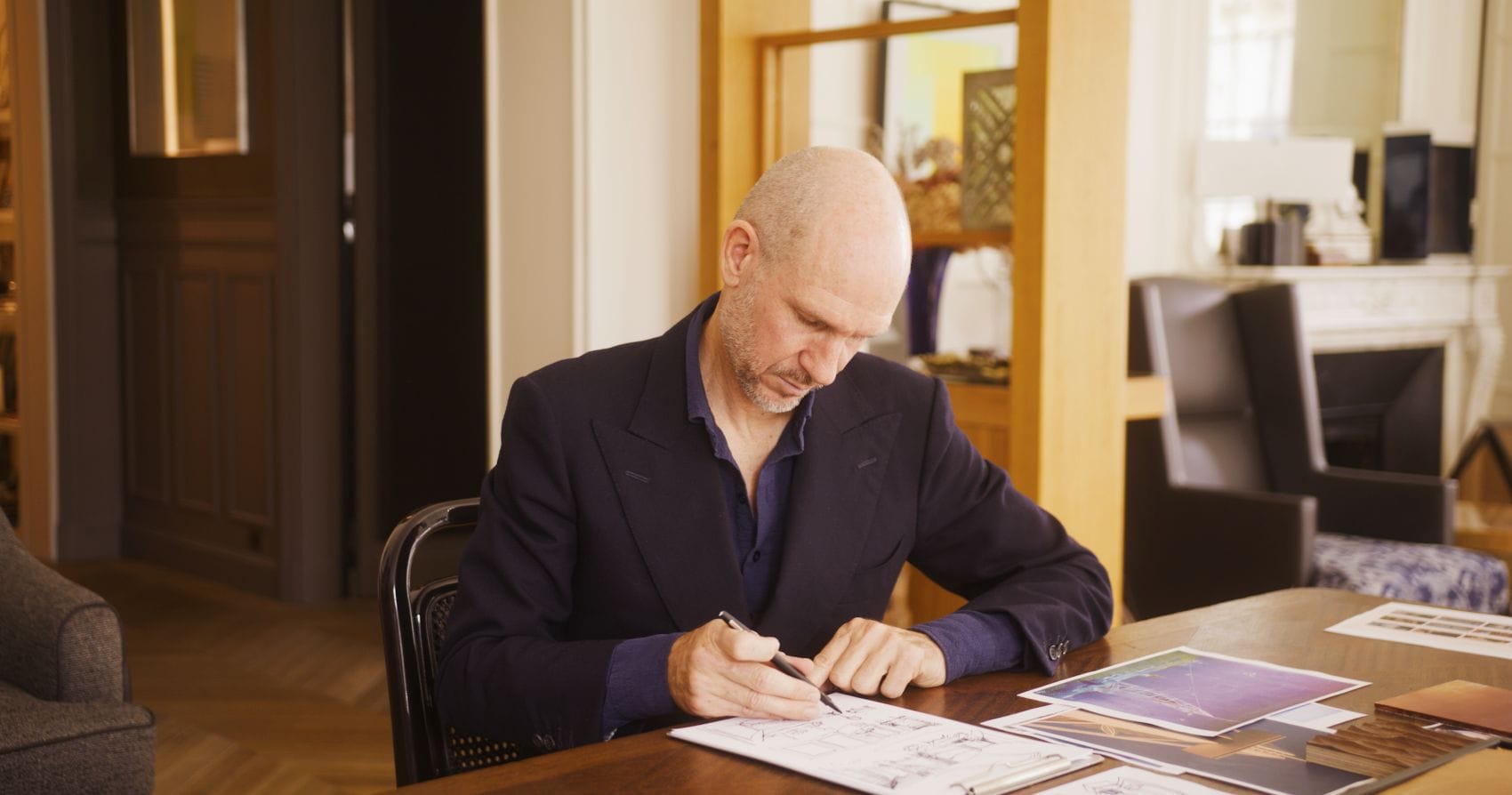 Hoteldesigner Tristan Auer sitzt am Schreibtisch und arbeitet an Skizzen