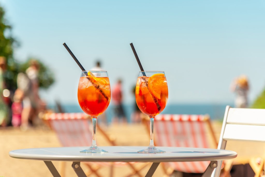 Zwei Gläser Aperol Spirtz stehen auf einem Tisch im Freien.