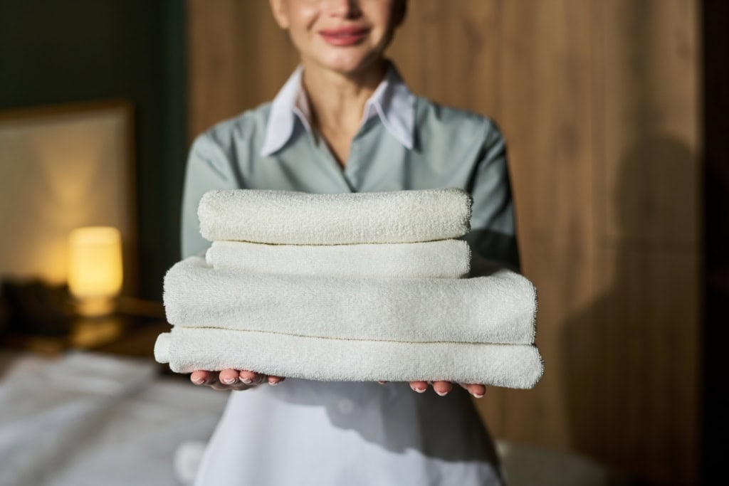 Frau reicht Handtücher im Hotel